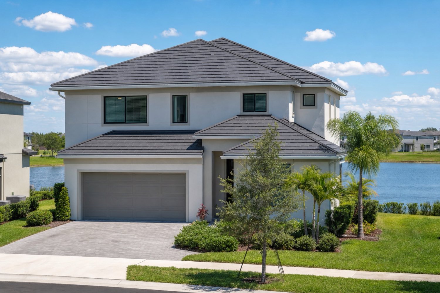 Two-story Orlando home with a carbon-gray shingle-profile metal roof by a pond
